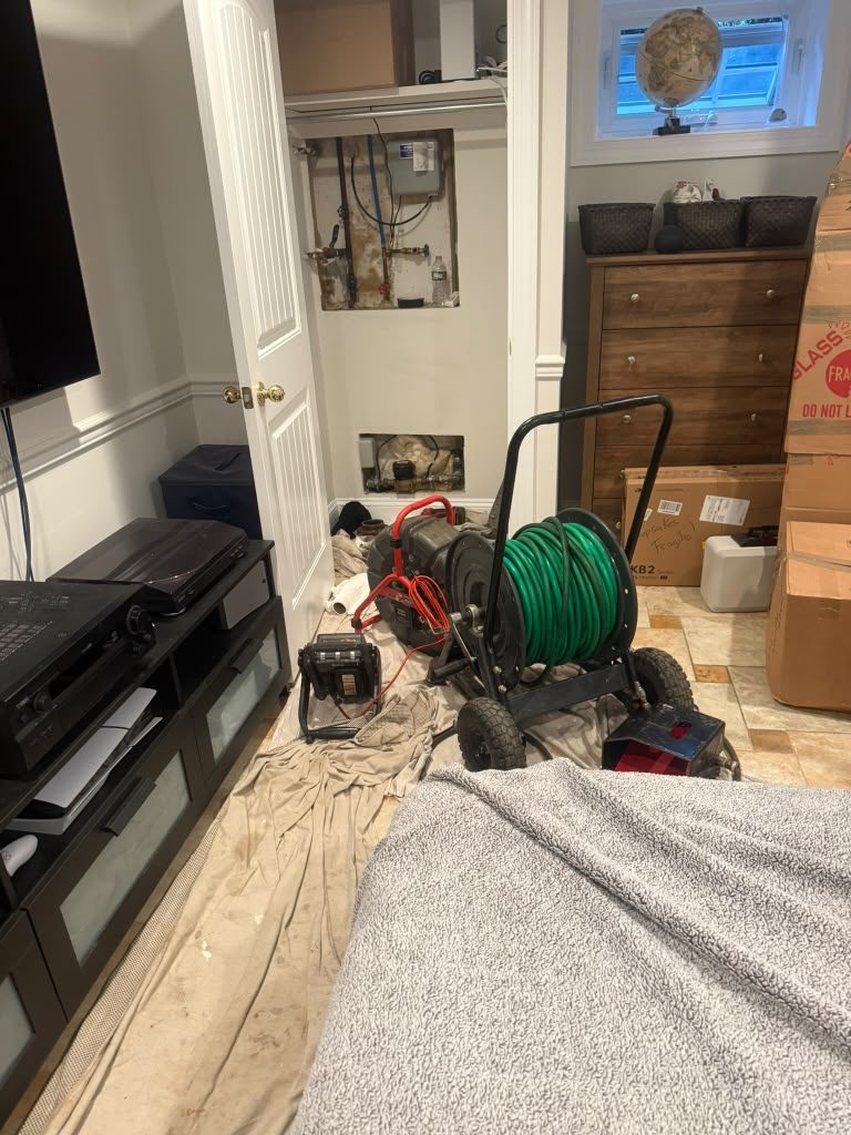 Equipment and a hose reel set up on protective sheeting in a furnished room.